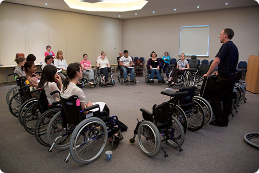 class organised in a circle of wheelchairs listening to instructor